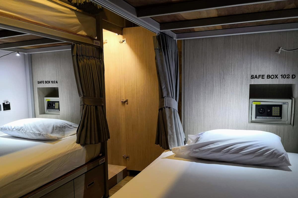 Une cabine équipée de deux lits, chacun avec un oreiller et une tête de lit. On y trouve également deux coffres-forts portant les numéros 102A et 102D.