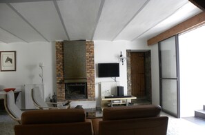 Una sala de estar con chimenea, televisor y un amplio ventanal.