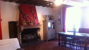A cozy room with a fireplace, a dining table with chairs, and a sofa.