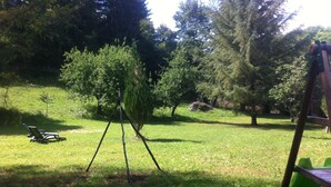 A grassy outdoor area with a swing set, a small tree, and a bench.