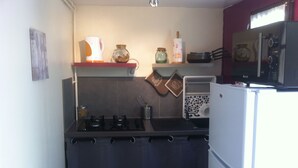 A compact kitchen with a gas stove, a microwave, and a refrigerator.