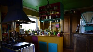 Una cocina con estufa, repisas con frascos y una ventana.