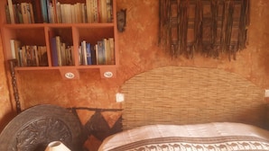 Una habitación con una estantería, una colcha estampada y una lámpara.