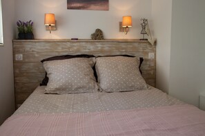 A bedroom with a wooden headboard, two wall-mounted lamps, a heart-shaped decoration, and a mannequin. - Apartment in residence, sea view and Cap Canaille (Cassis)