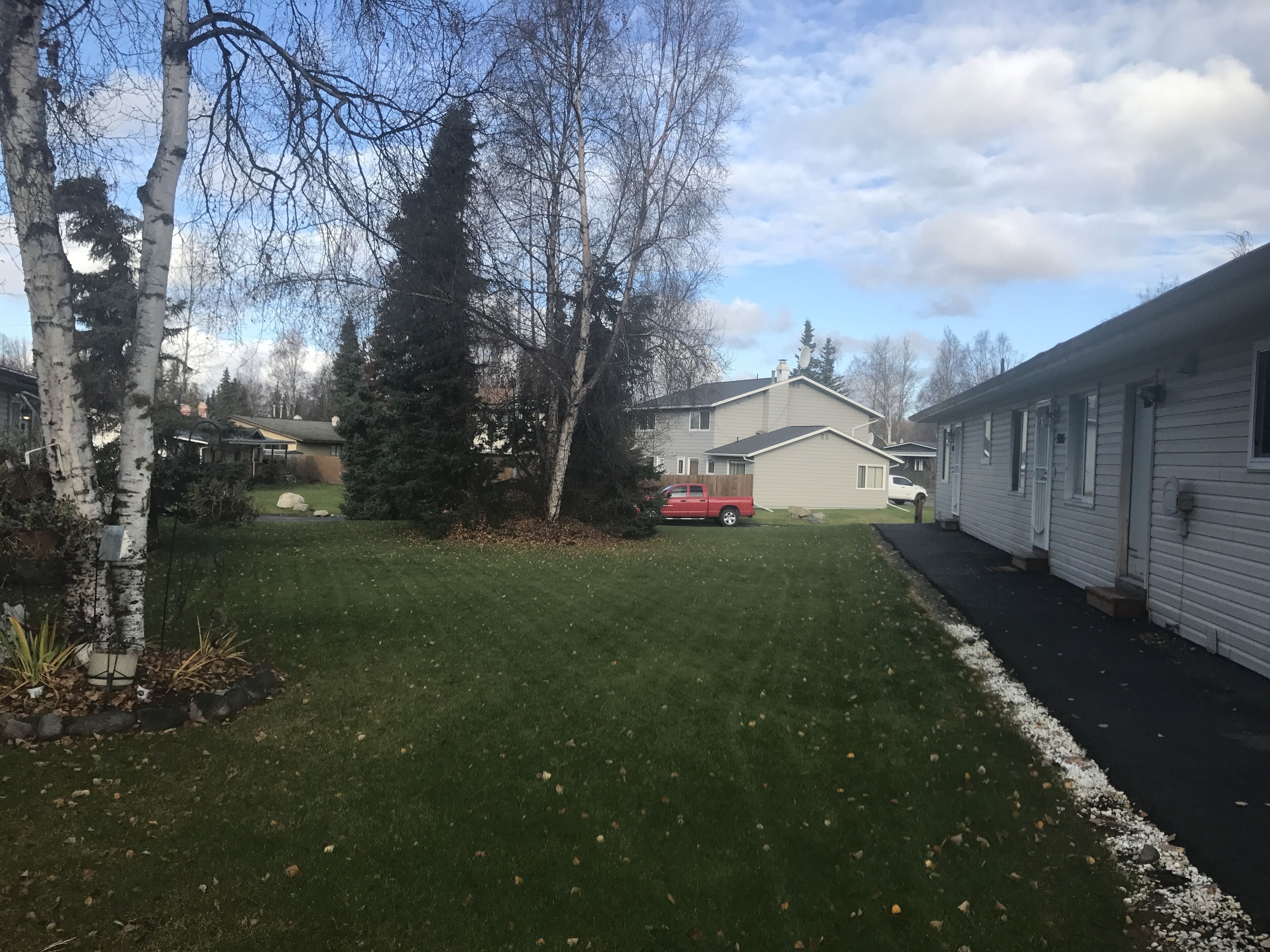 A residential area with a grassy yard, a red truck, and a mobile home.