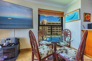 Ein Zimmer mit Glastisch, Korbstühlen, Fernseher und Meerblick.