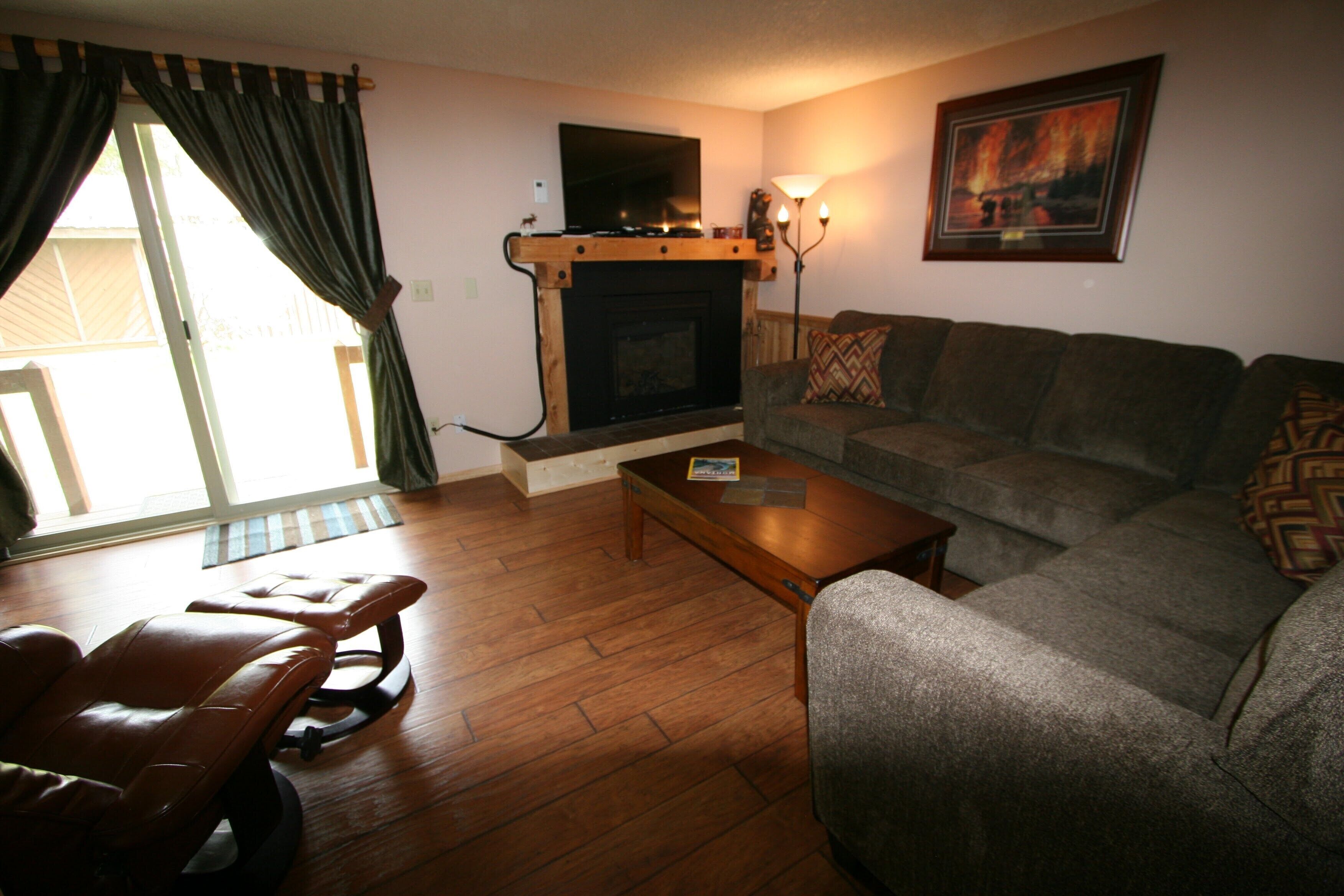 Un salon avec une cheminée, un canapé, une table basse et un fauteuil inclinable.