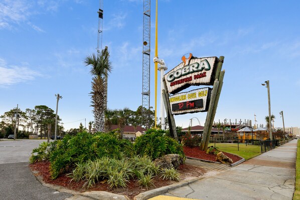 A sign for Cobra Adventure Park with a digital display indicating 1 PM.