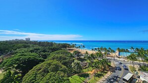 A coastal view with a beach, palm trees, and a road leading to a building. - 〰Waikiki〰Studio w/Spectacular Views & Balcony-WAIKIKI GRAND HOTEL® 712 (Honolulu)