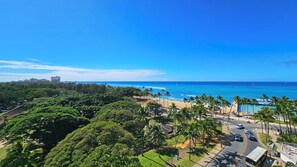 A coastal view with a beach, palm trees, and a road leading to a building. - 〰Waikiki〰Studio w/Spectacular Views & Balcony-WAIKIKI GRAND HOTEL® 712 (Honolulu)