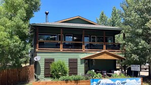 A two-story building with a green exterior, a wooden balcony, and a sign reading "11 Granada Ct." - Ravens Fun Bunkhouse for up to 6, Dbl Bathroom, W/D, Patio w/ Fire Pit & Grill (Westcliffe)