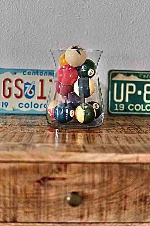 A glass jar filled with various colored billiard balls on a wooden surface.