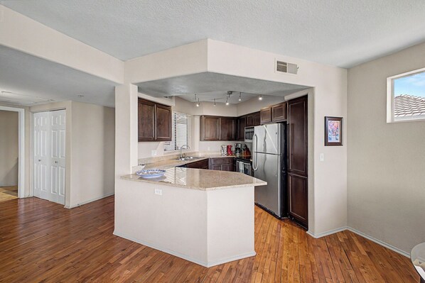 Una cocina moderna con una isla central, armarios de madera oscura, electrodomésticos de acero inoxidable y vistas al exterior.