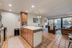 A modern kitchen with wooden cabinets, a large island, and a dining area with a view.