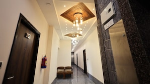 A hotel hallway with a wooden ceiling, a fire extinguisher, and an elevator.