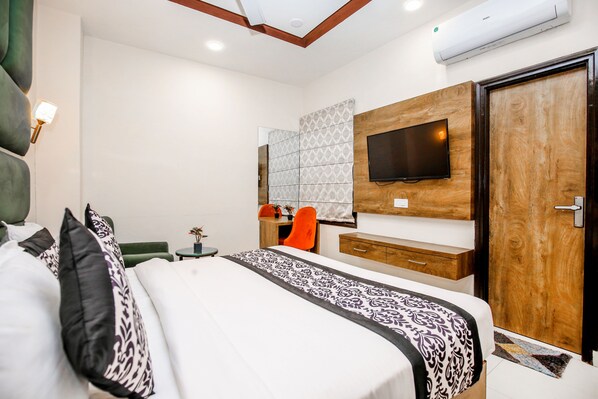 Una habitación de hotel moderna con una cama grande, un televisor montado en un panel de madera, un escritorio con una silla y un armario.
