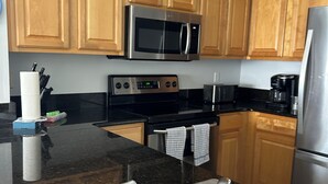 A kitchen with wooden cabinets, a stainless steel sink, a microwave, and a coffee maker. - Gulf Front Condo, Corner Unit, Stunning Views, Great Restaurants (Panama City Beach)