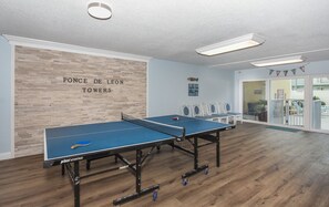 A ping pong table in a room with a wooden floor and a wall with the text "PONCE DE LEON TOWERS".
