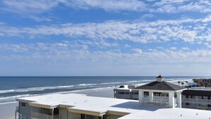 Un hôtel en bord de mer offrant une vue sur la plage, doté de nombreux balcons et bénéficiant d'un ciel dégagé.
