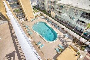 A rooftop pool with lounge chairs and a view of adjacent buildings.