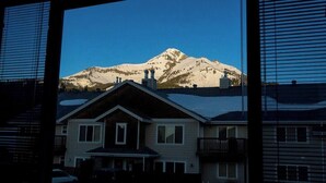 A house with a mountain in the background, a balcony, and a garage. - Cozy 2BR/2BA Condo at Big Sky Resort (Big Sky)