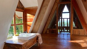 A wooden interior with a large window, a sink, and a bench.