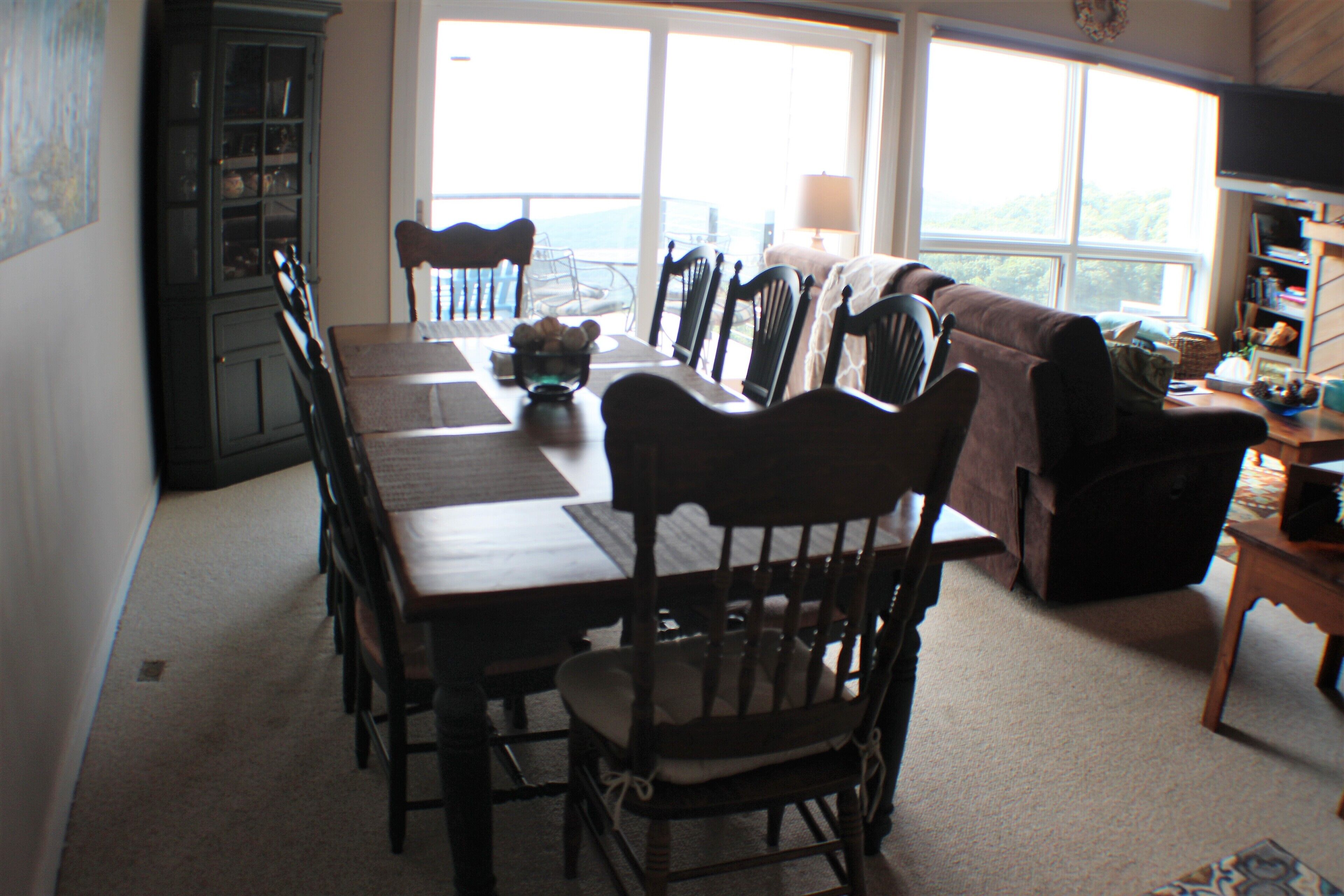 A dining area with a long table, chairs, and a cabinet.