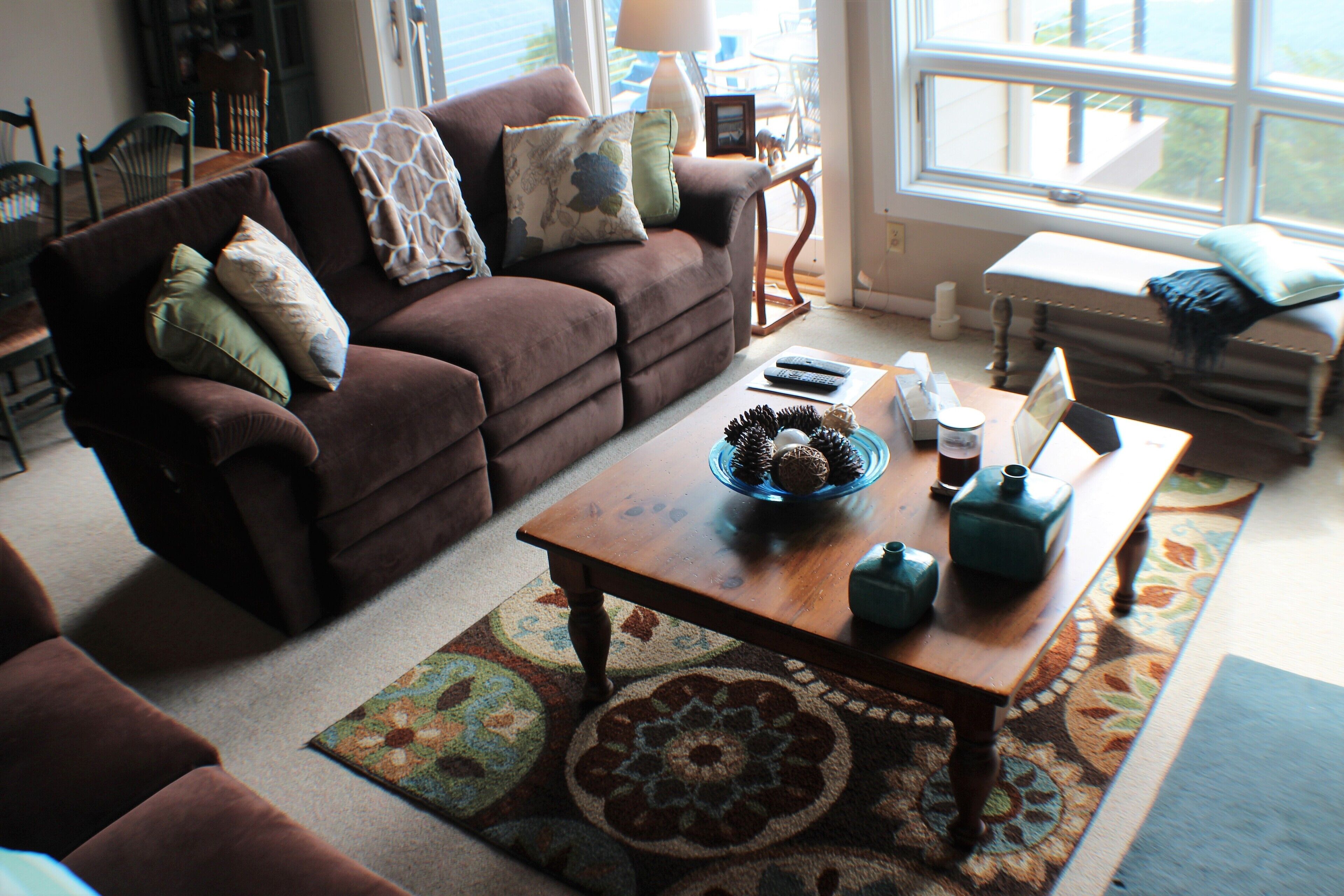 A cozy living room with a brown sofa, a wooden coffee table, and a patterned rug.