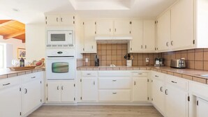 A modern kitchen with white cabinets, a microwave, oven, and a coffee maker.