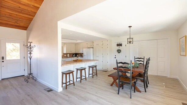 A spacious kitchen with white cabinets, a wooden countertop, and a dining area with a wooden table and chairs.