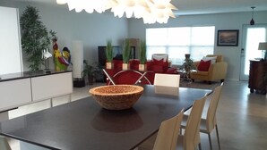 A modern kitchen with a dark countertop, a woven basket, and a dining area with chairs and a table. - Vanderbilt Beach Vacation Home - LARGE PRIVATE POOL w/ fully fenced in backyard (Naples)