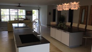 A modern kitchen with a central island, a built-in sink, and a ceiling fan. - Vanderbilt Beach Vacation Home - LARGE PRIVATE POOL w/ fully fenced in backyard (Naples)