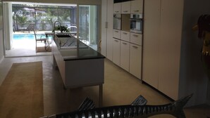 A modern kitchen with a central island, white cabinets, and a view of a swimming pool. - Vanderbilt Beach Vacation Home - LARGE PRIVATE POOL w/ fully fenced in backyard (Naples)