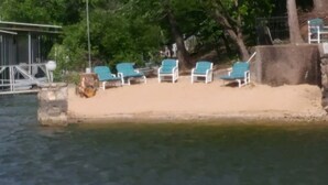 A sandy beach with several blue lounge chairs aligned in a row. - Private Paradise spot !!  (Osage Beach)