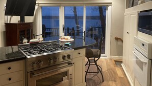 A kitchen with a gas stove, oven, and a dining area with a table and chairs. - Private Paradise spot !!  (Osage Beach)