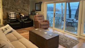 A living room with a stone wall, leather recliner, brown armchair, and a coffee table. - Private Paradise spot !!  (Osage Beach)