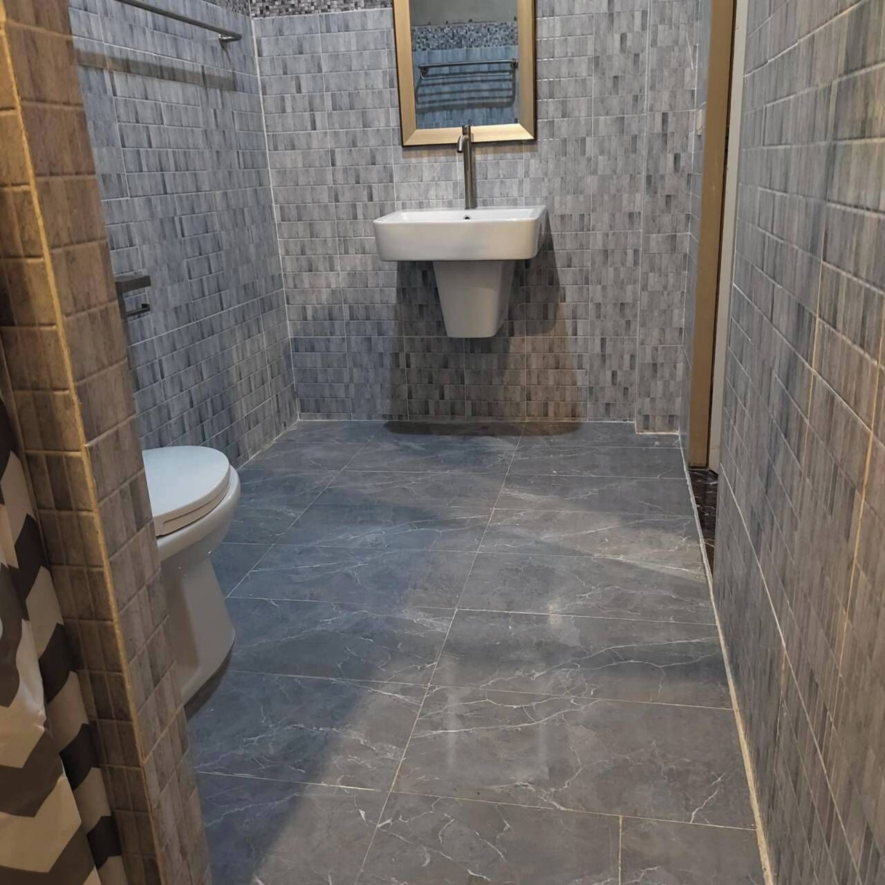 A bathroom with a toilet, a sink, and tiled walls.