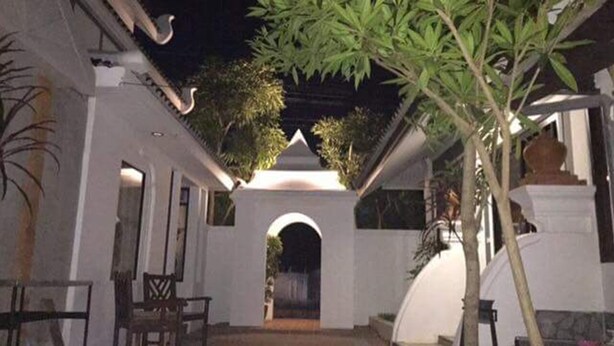 A corridor with a central archway leading to a building, surrounded by white walls and potted plants. - Phu View Hideaway (Kantharalak)