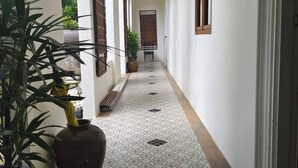 A hallway with patterned floor tiles, potted plants, and a wooden bench. - Phu View Hideaway (Kantharalak)