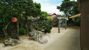 A garden with a stone wall, a large plant, and a bicycle. - Kohamaso (Taketomi)