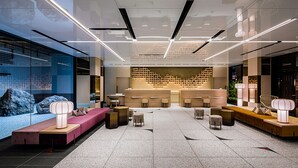 Un hall d’entrée moderne comprenant un comptoir d’accueil, des espaces de détente et un mur décoratif.