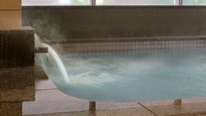 Un bain à remous avec une structure extérieure en pierre, un intérieur carrelé et une fenêtre en arrière-plan.