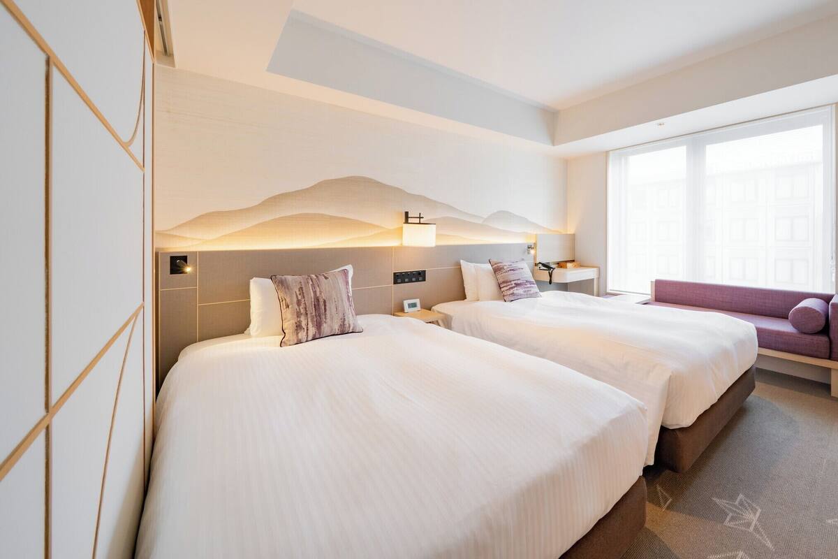 Une chambre d’hôtel avec deux lits, un canapé, une télévision et une grande fenêtre.