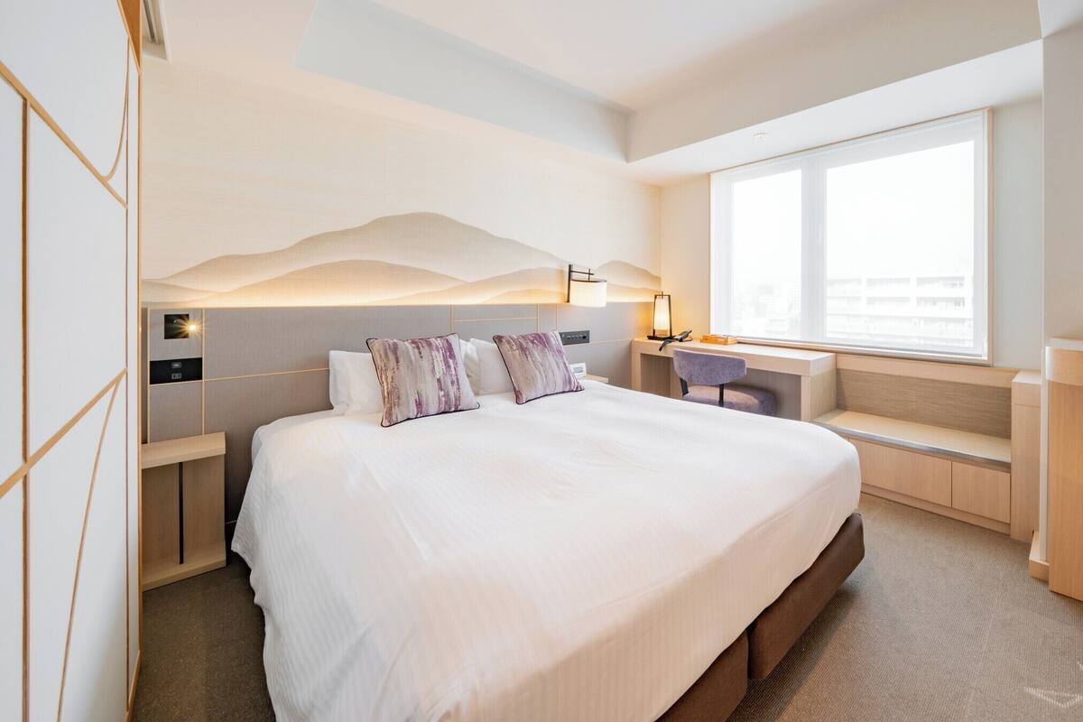 Une chambre d’hôtel moderne avec un grand lit, un bureau et une fenêtre.