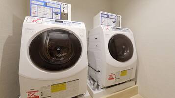 Two front-loading washing machines in a laundry room with control panels and safety instructions.