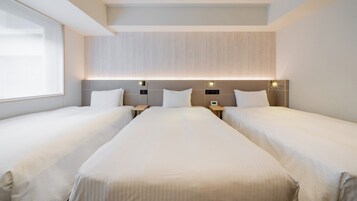 A hotel room with two single beds, a large window, and a modern headboard with built-in lighting.