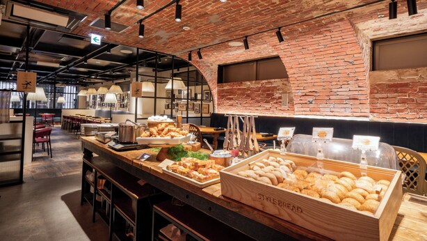 Un comptoir de boulangerie où sont exposés divers produits de boulangerie, avec un mur de briques rustiques en arrière-plan.