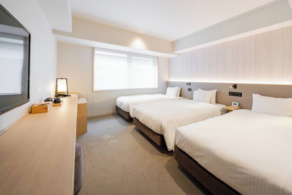 Une chambre d’hôtel avec deux lits, un bureau, une télévision et une fenêtre.