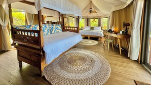 A spacious bedroom with a four-poster bed, a desk, and a chair, featuring a large woven rug and a ceiling fan. - Palau Carolines Resort (Meyungs)