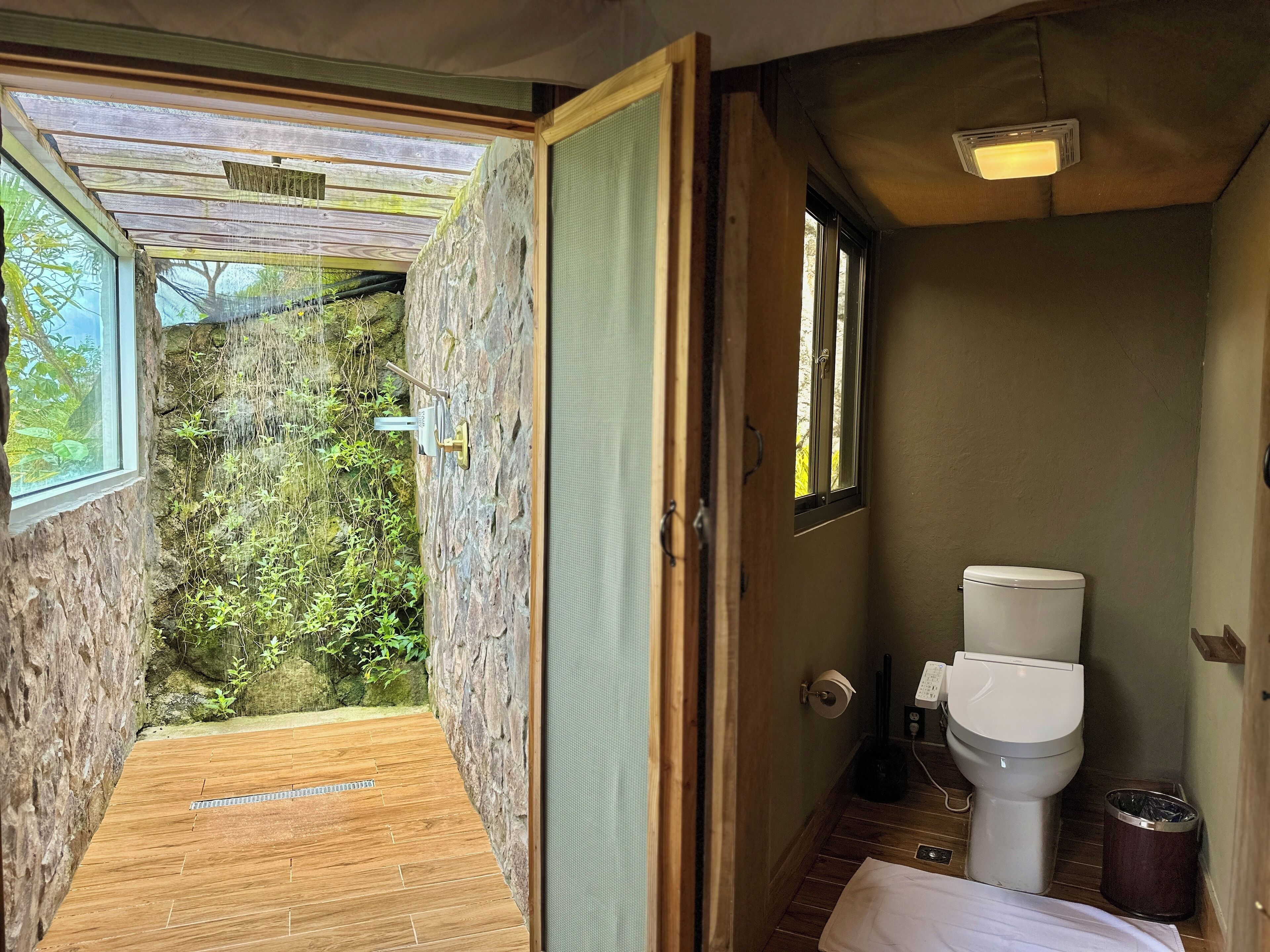 A bathroom with a toilet, a trash bin, and a window.
